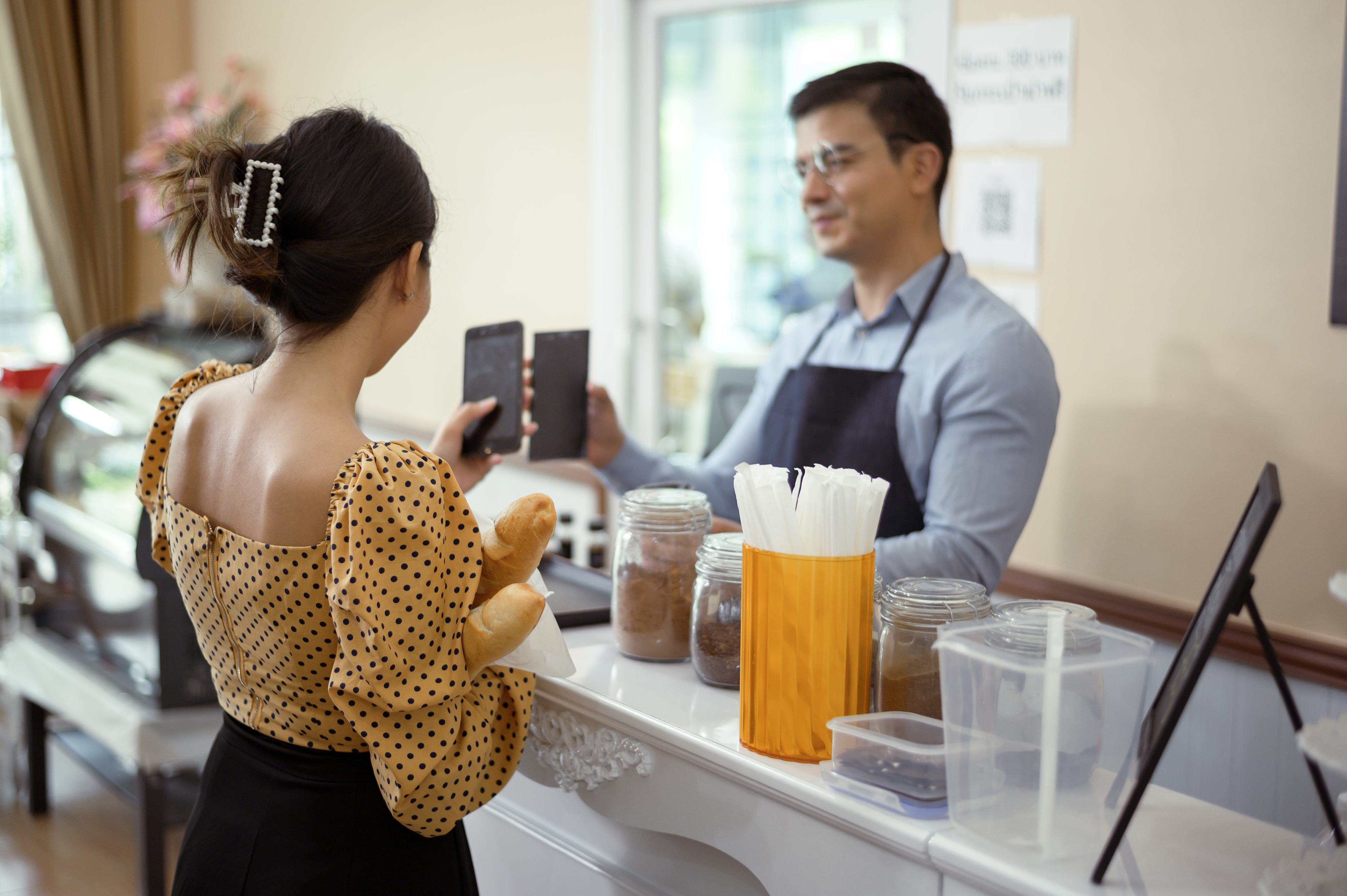 a bakery guest is collecting reward points from the owner at the counter using loyalty program app