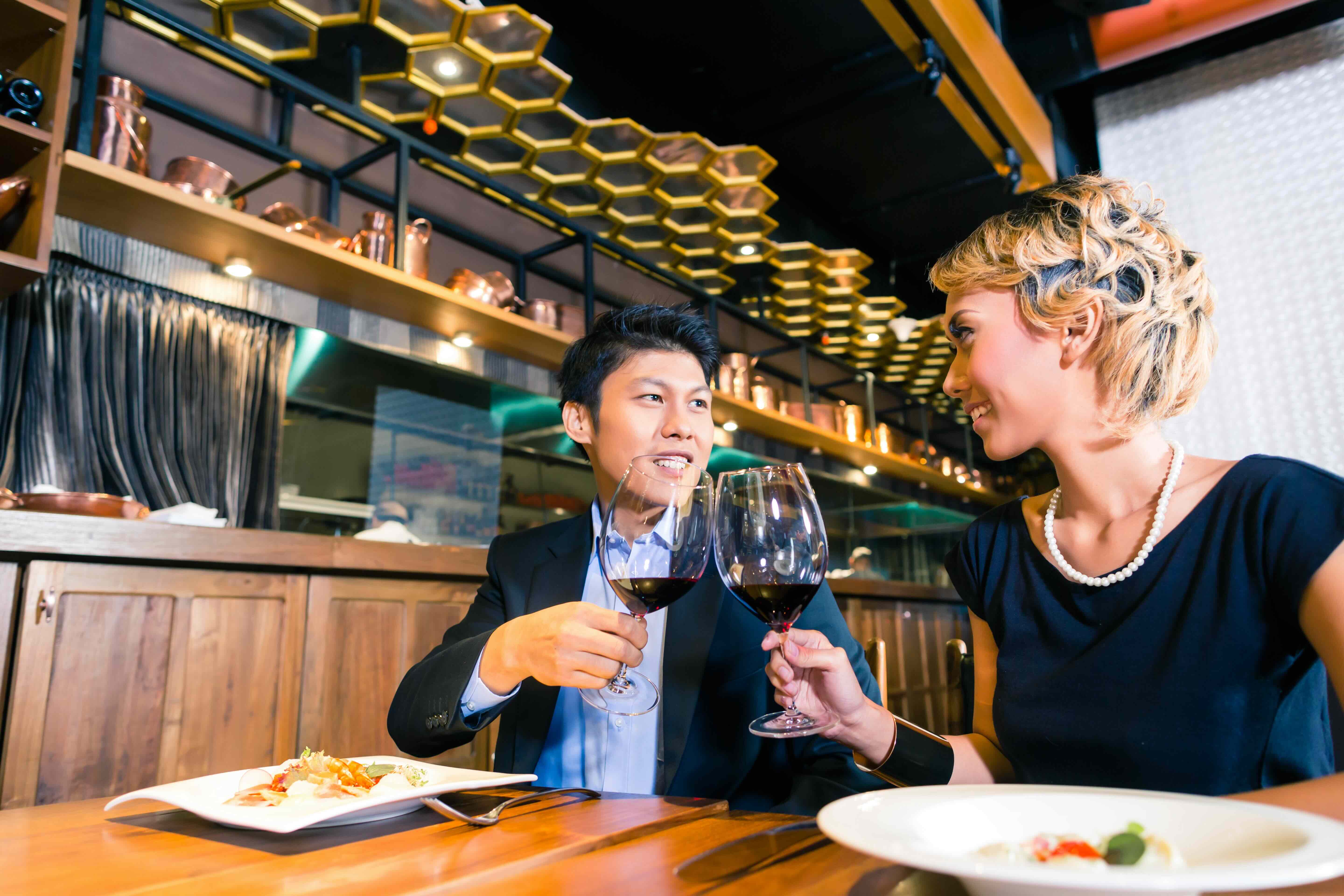 asian couple toasting to each other with red wine