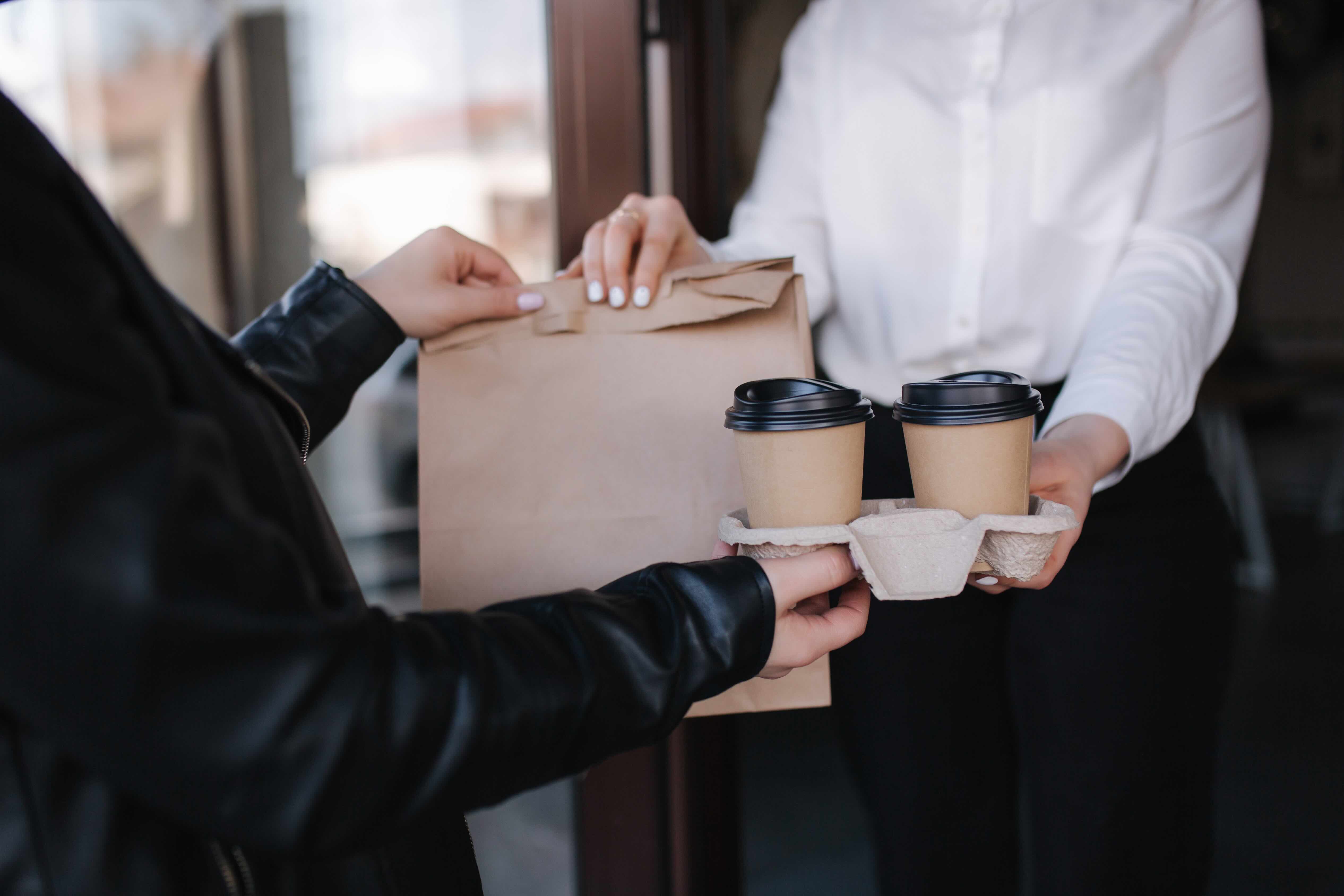 cafe staff hand over packages to food delivery