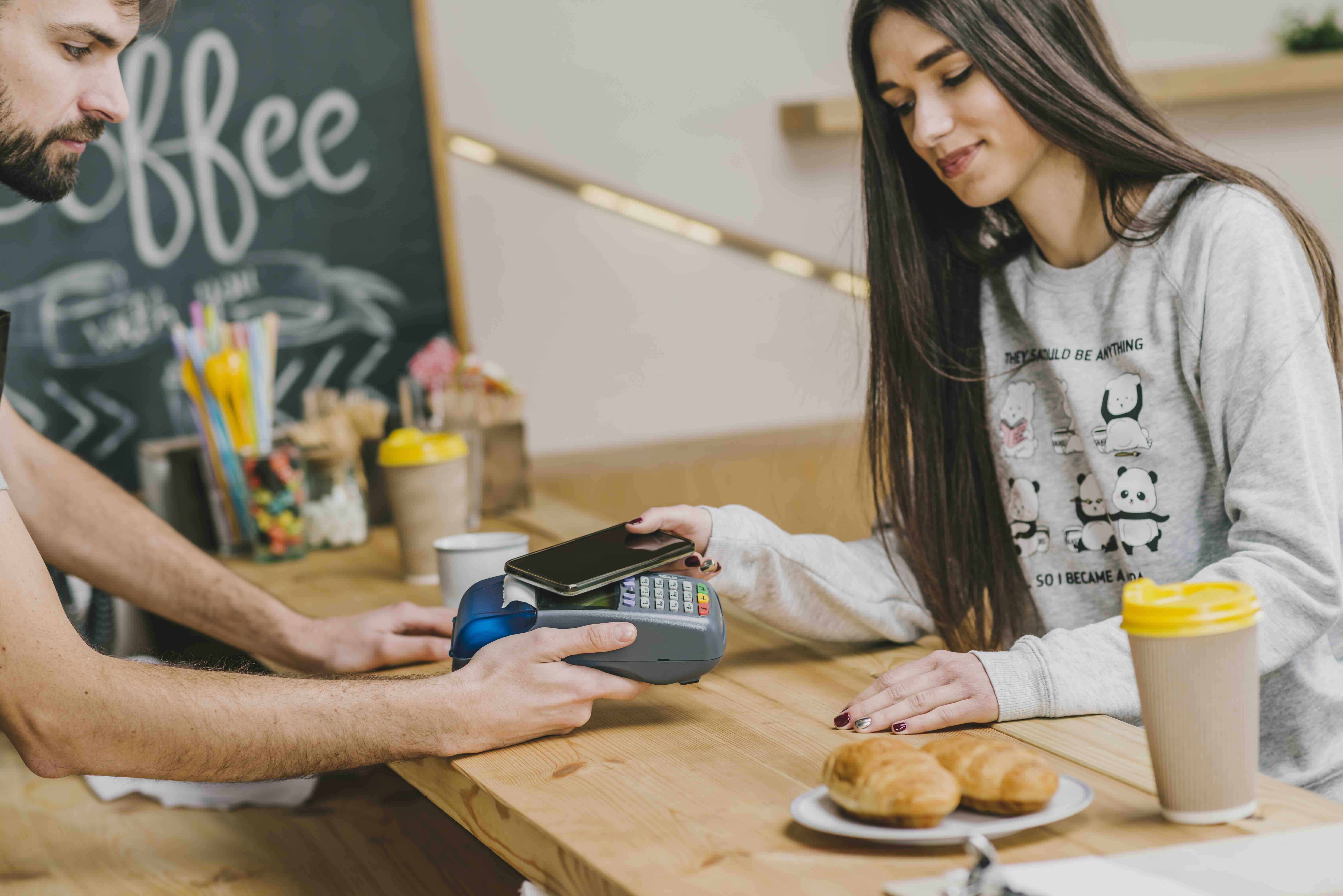 female guest paying with mobile phone in a cefe