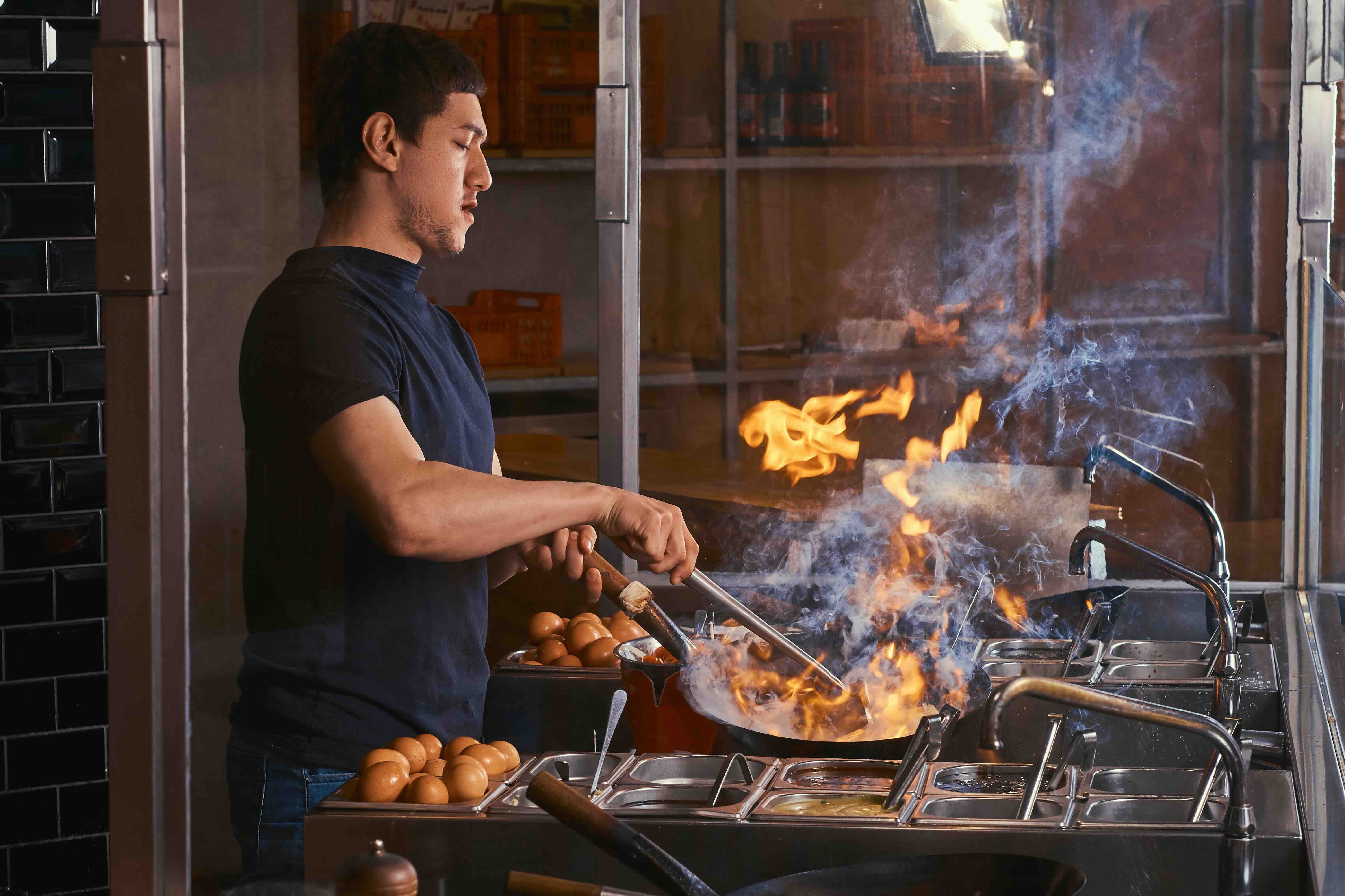 chef doing stir fry in a commercial kitchen